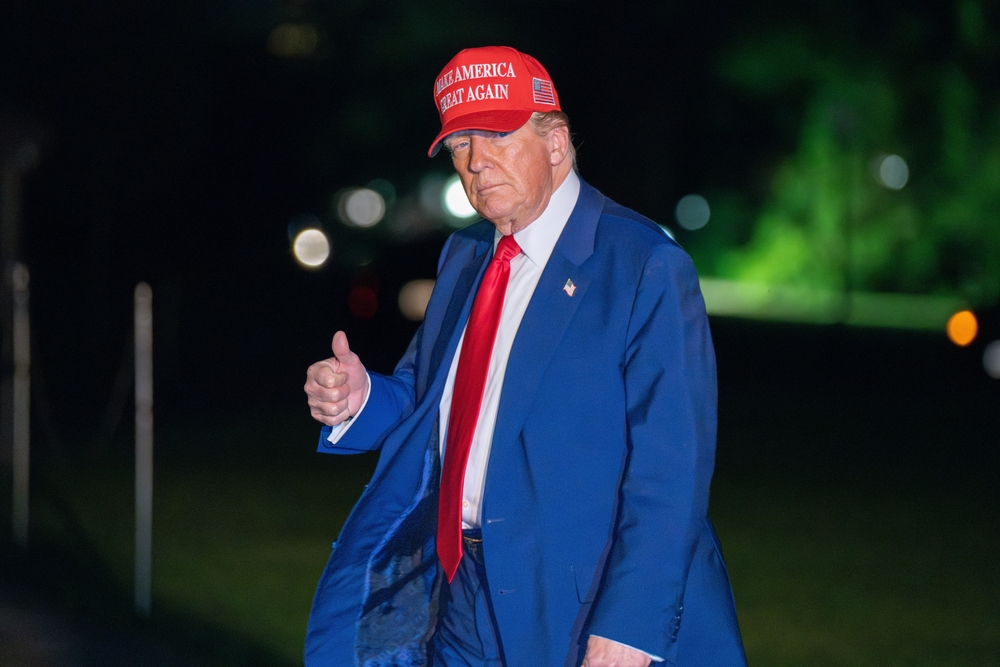 shutterstock_2620657023 | TVGURU.cz Donald Trump v modrém obleku a červené kšiltovce, večer, v šeru