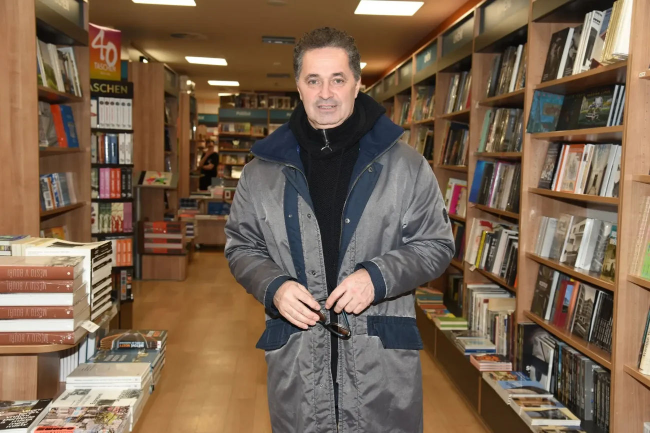 Martin Dejdar stojící v knihkupectví mezi regály.