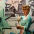 Lucille Ball ve voskovém muzeu Madame Tussaud v New Yorku - figurína se zrzavými vlasy v bleděmodrých šatech, s plakáty v pozadí.