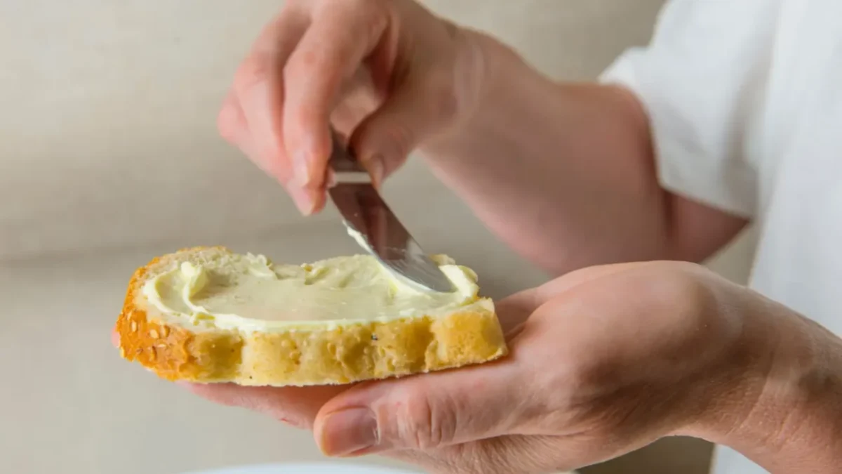 osoba si natírá chleba margarínem