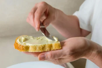 osoba si natírá chleba margarínem