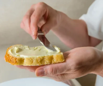 osoba si natírá chleba margarínem