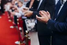 lidé stojí podél červeného koberce a tleskají