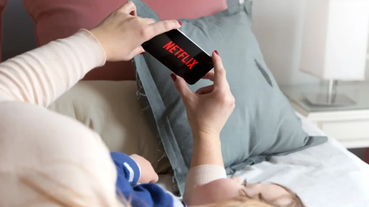 Lidé sledující Netflix v posteli.