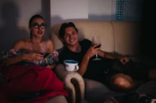 Žena s mužem sedí ve tmě na gauči.