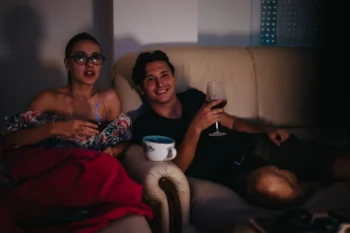 Žena s mužem sedí ve tmě na gauči.