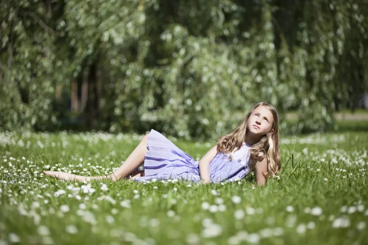 Holčička leží v trávě.