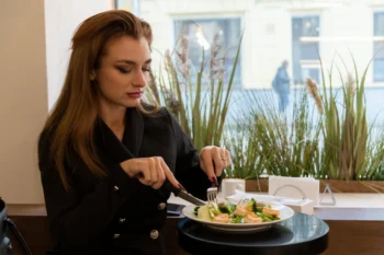 Elegantní žena - dlouhovlasá hnědovláska v černém - v bistru jí fazolový salát.