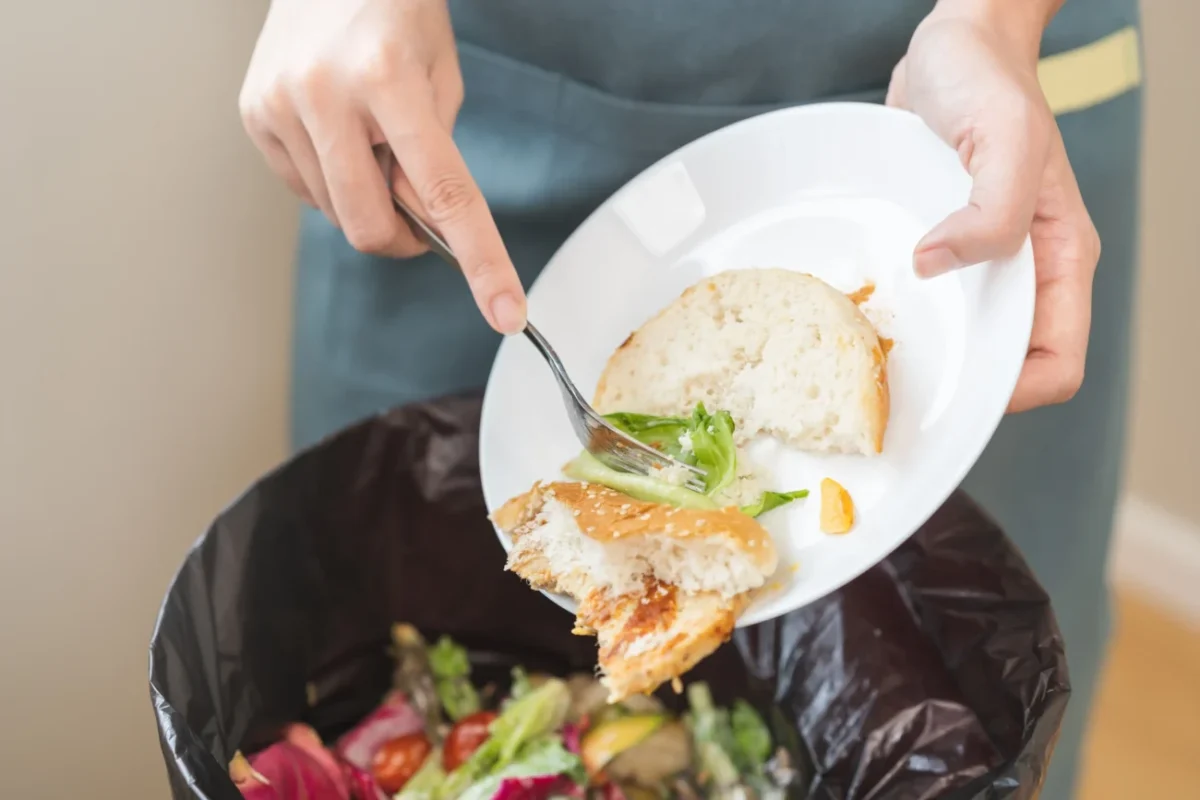Žena vyhazuje zbytky jídla do koše.