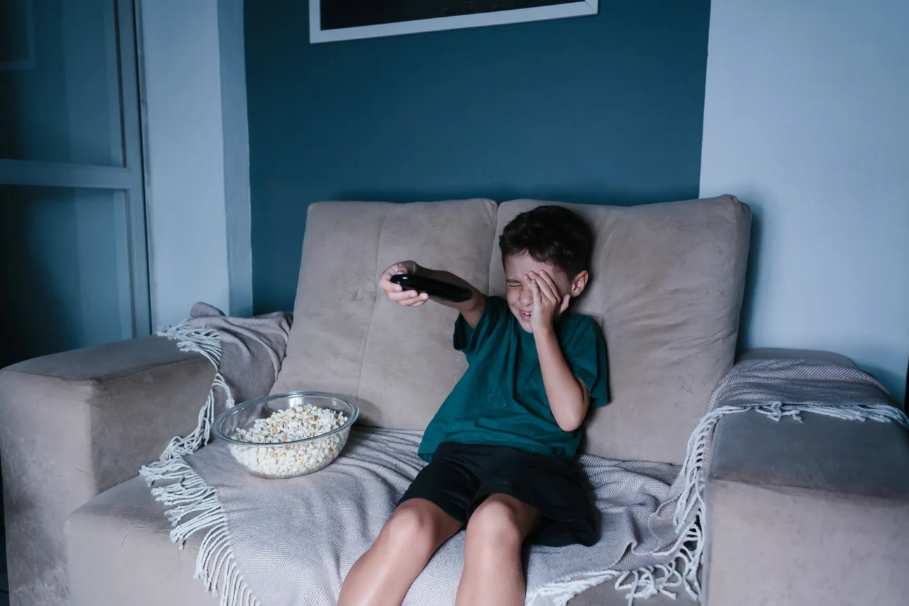 shutterstock_569695567-2 | TVGURU.cz Vystrašený chlapec sedí na gauči s ovladačem v ruce.