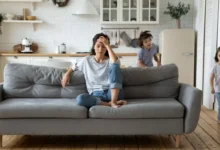 Žena sedící na gauči, okolo pobíhají děti.