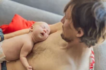 muž leží s miminkem na hrudi