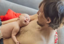 muž leží s miminkem na hrudi