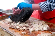 Ruce člověka krájející maso.