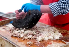 Ruce člověka krájející maso.