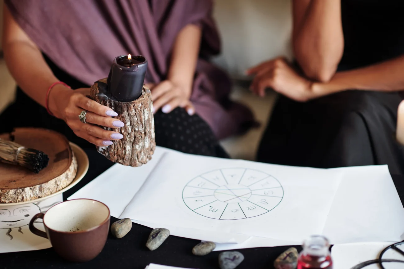 Žena drží svíčku nad astrologickým vizuálem. 
