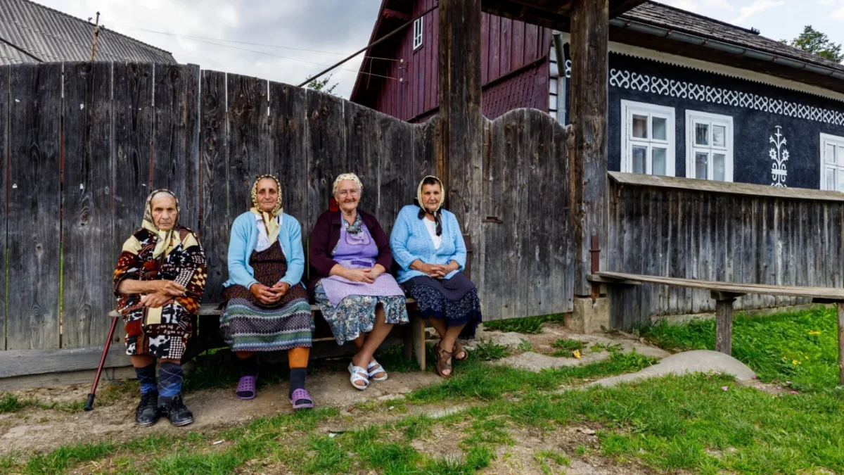 Babičky sedící na lavičce ve vesnici.