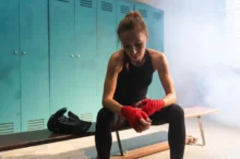 Žena sedící na lavičce v šatně.