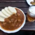 Bílý talíř s gulášem a knedlíkem + pivem na dřevěném stole