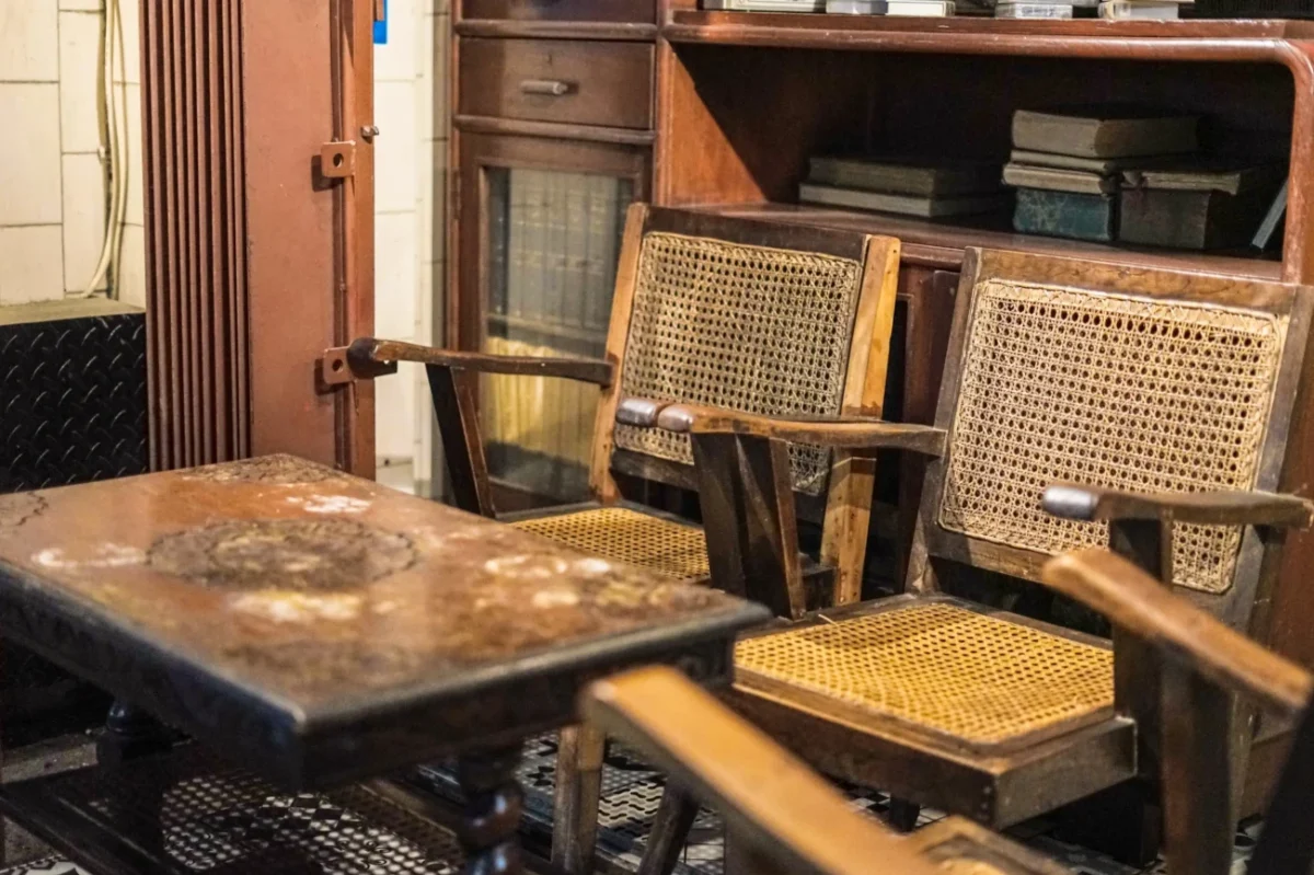 Starý stůl stojí vedle starých židlí.