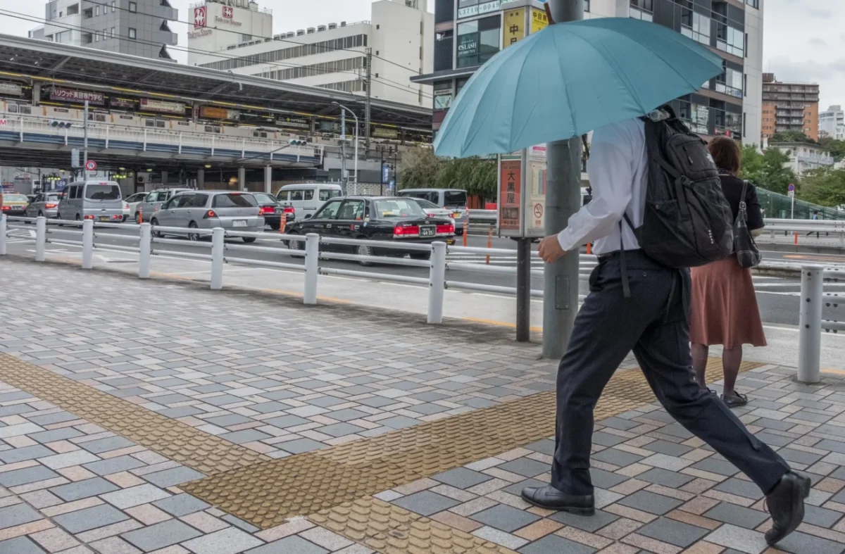 muž jde po deštivé ulici s deštníkem nad hlavou