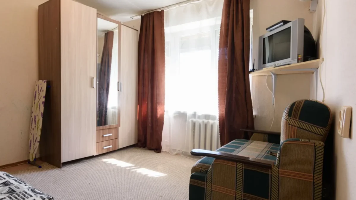 fotka skromného bytu s televizí, křeslem a skříní