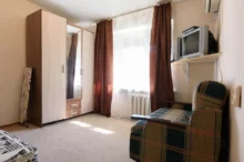 fotka skromného bytu s televizí, křeslem a skříní