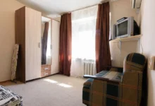 fotka skromného bytu s televizí, křeslem a skříní