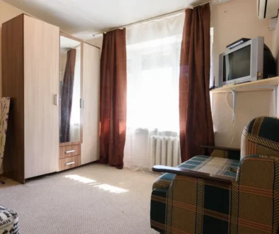 fotka skromného bytu s televizí, křeslem a skříní