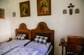 Stará chalupa, ve které stojí postele a na zdi visí obrazy.