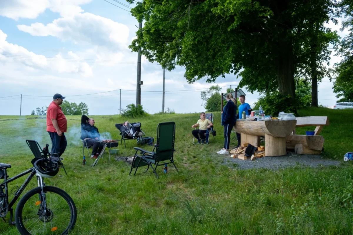 Lidé táboří na louce.