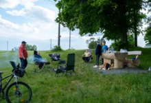 Lidé táboří na louce.