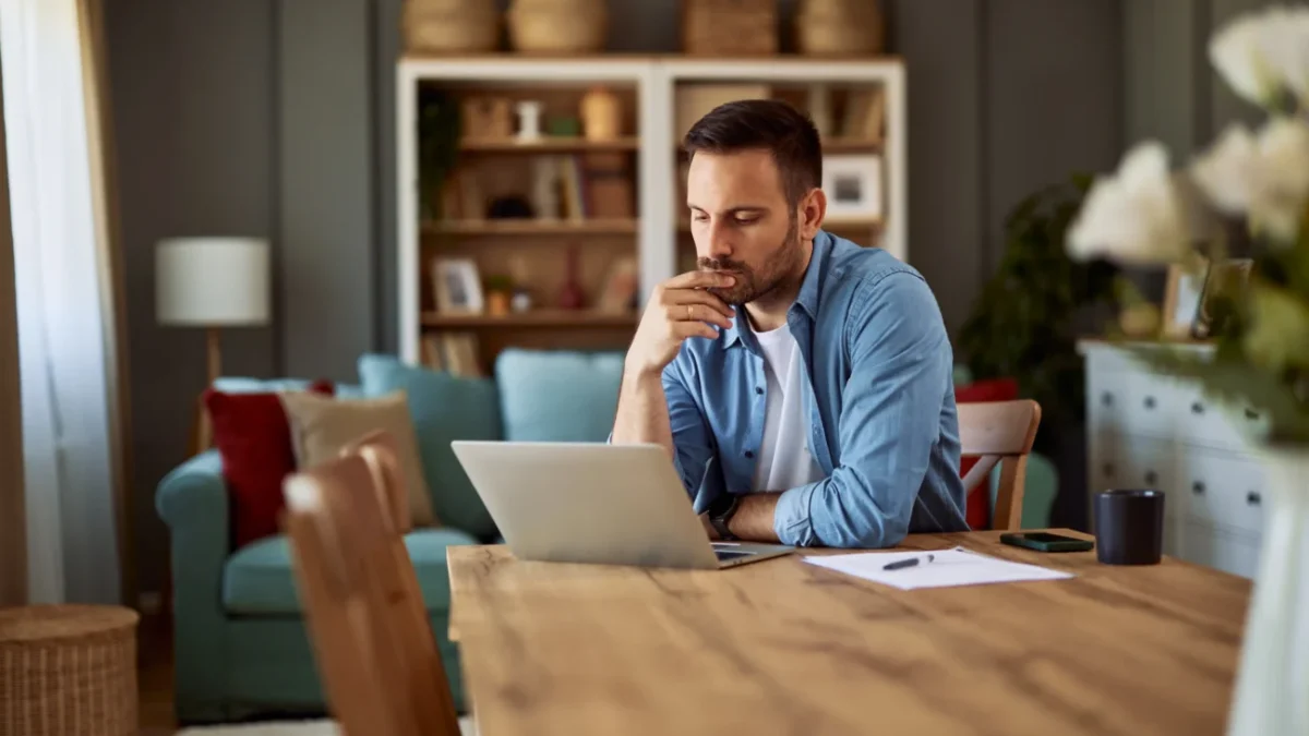 Muž sedí u notebooku a přemýšlí.