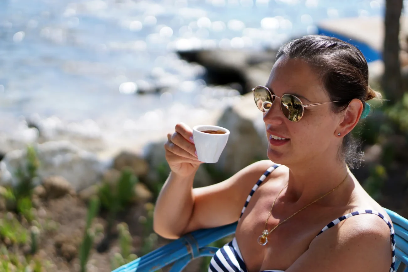 Žena venku popíjí kávu.