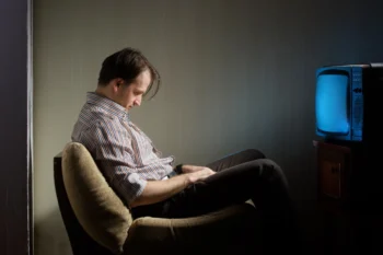 Muž usnul na židli před televizí.