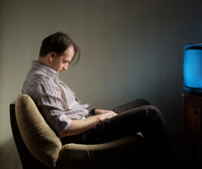 Muž usnul na židli před televizí.