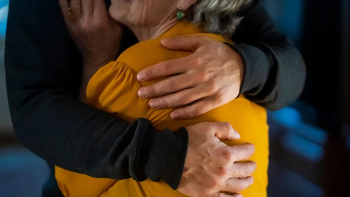 Muž drží starší ženu v objetí.