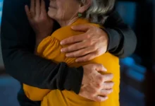 Muž drží starší ženu v objetí.