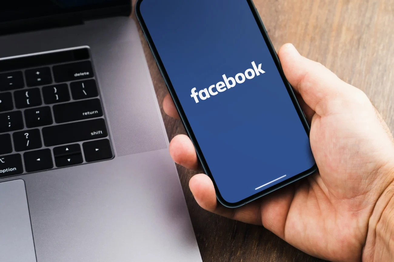 shutterstock_2052153839-2 | TVGURU.cz Člověk v ruce drží telefon, na kterém je otevřený Facebook.