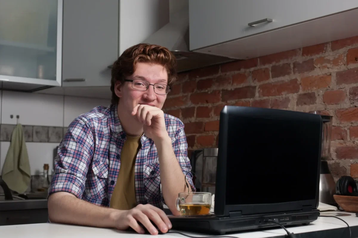 Muž sedí v kuchyni u notebooku.