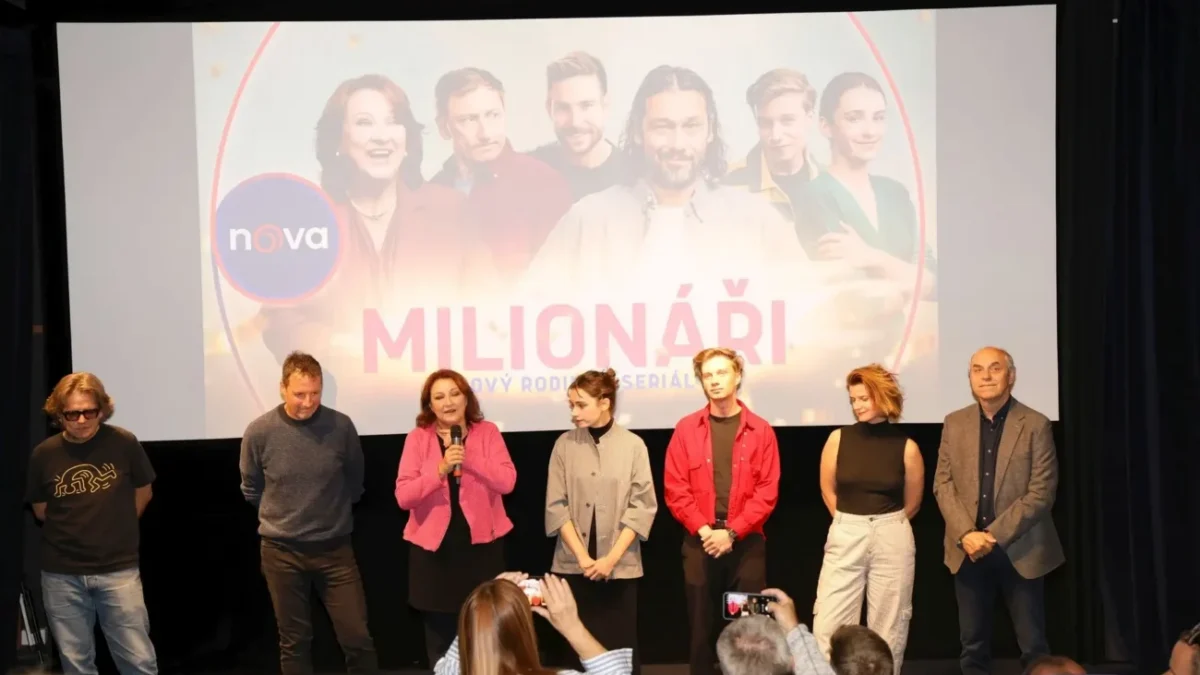 herci ze seriálu Milionáři stojící před plátnem