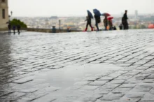 Kaluž na pražské ulici (dlažební kostky, odpoledne, výhled na Prahu)