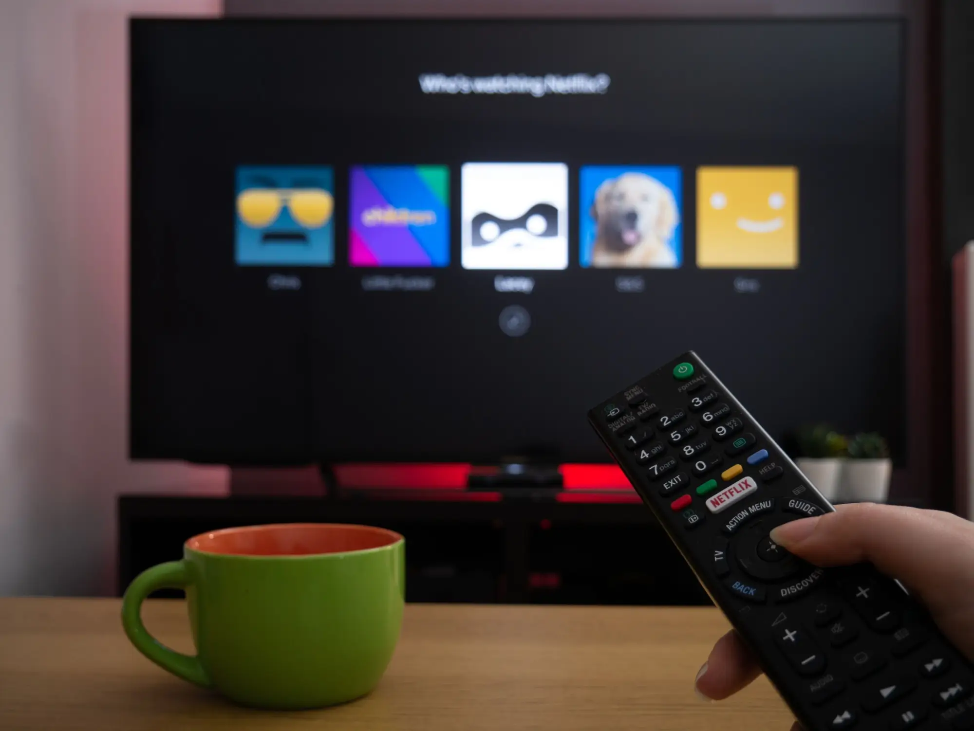 osoba drží ovladač před televizí s Netflixem