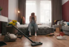 Žena sedí na posteli a má ruku složenou v dlaních.