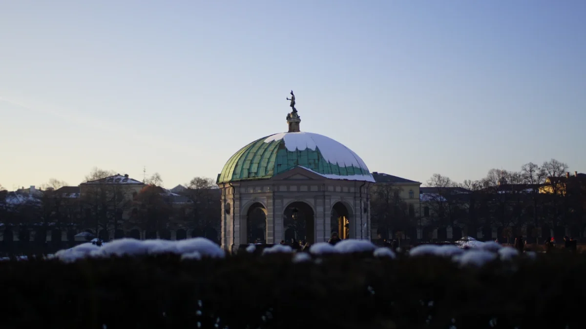 Mnichov, Hofgarten: zimní scéna slavné Zahrady u dvora (Schlossgarten) a Dianina chrámu (Dianatempel) v centru města, s bílým sněhem a modrou oblohou