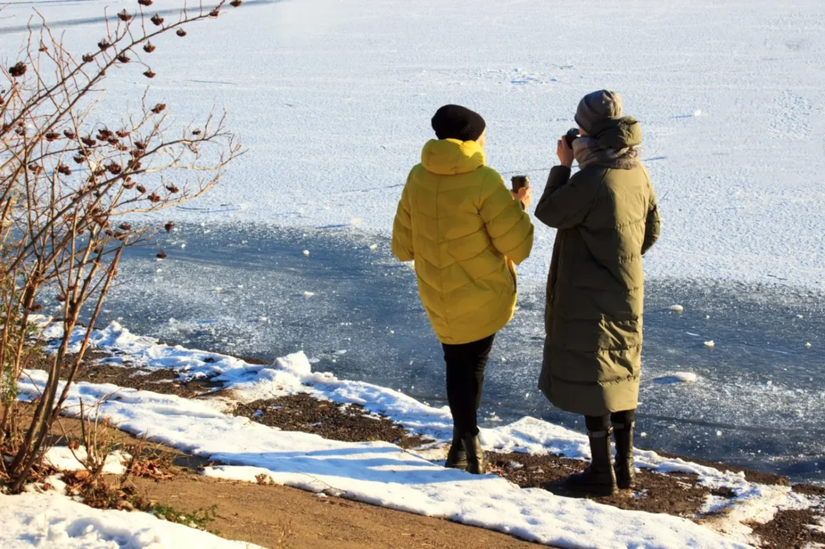 dvě ženy v teplém oblečení pijí kávu v zimní krajině