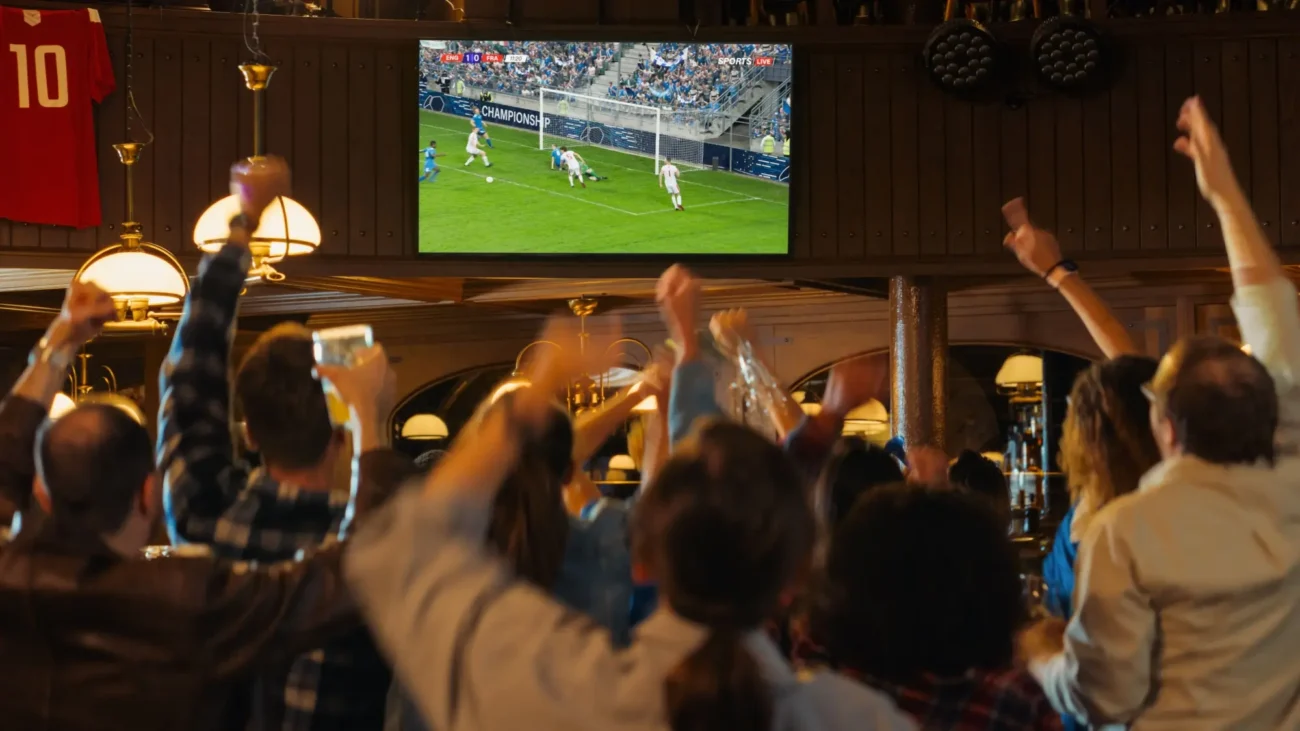 prostřední | TVGURU.cz Diváci fotbalu v baru sledují svůj oblíbený zápas a fandí.