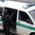 policejní dodávka u které stojí policista s dlouhou palnou zbraní