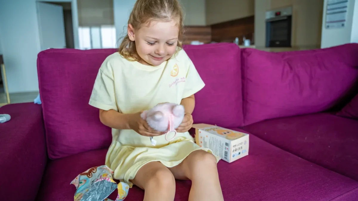 Holčička sedí na gauči a má na klíně Labubu.