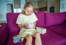 Holčička sedí na gauči a má na klíně Labubu.
